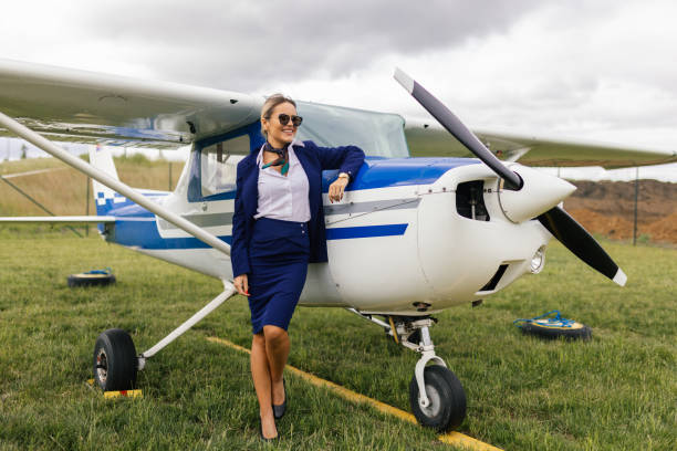 Young blond woman, stewardess standing in front of an airplane, getting ready for a flight.