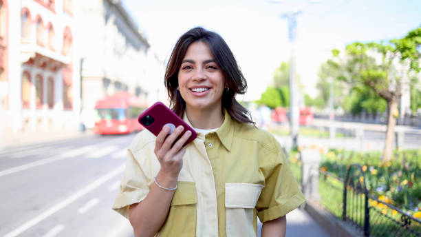 istock Young Latin woman walking and sending a voice message 2154519954