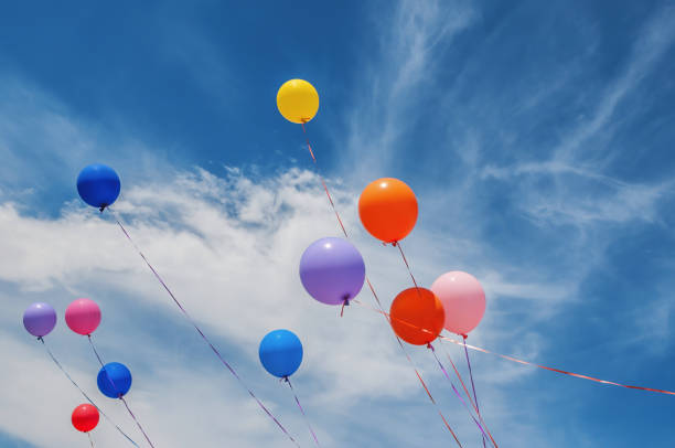 istock Colorful balloons floating free in a cloudy sky 2154524599