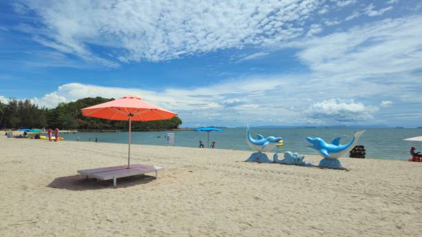 istock Beautiful tropical beach scenery, two sun beds and orange umbrella. White sand, blue sky clouds at Mui Nai beach, Ha Tien, Vietnam in summer. 2154532079