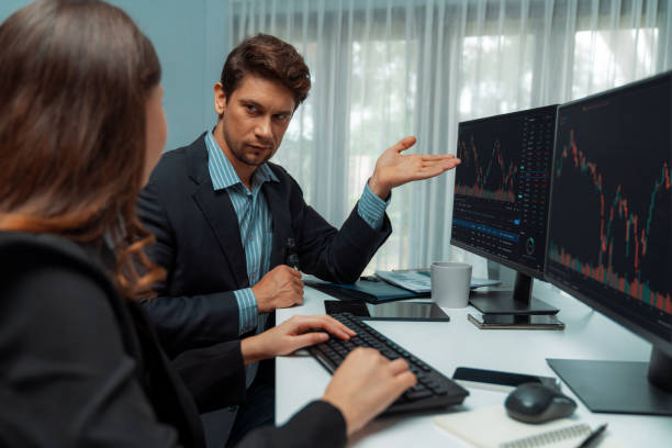 istock Two business traders in stock, woman checking to compare real time. Postulate. 2154532865