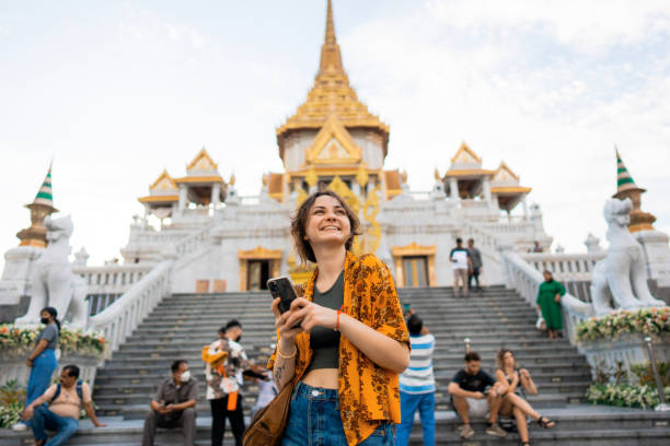 Woman using smartphone standing on the background of Wat Traimit