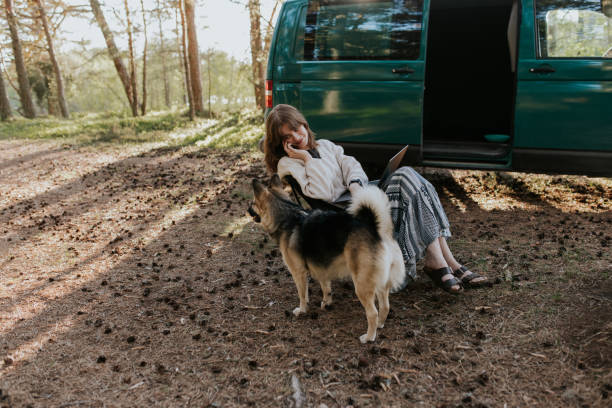 istock Young woman having a phone call while working remotely in the nature with her dog 2154546039