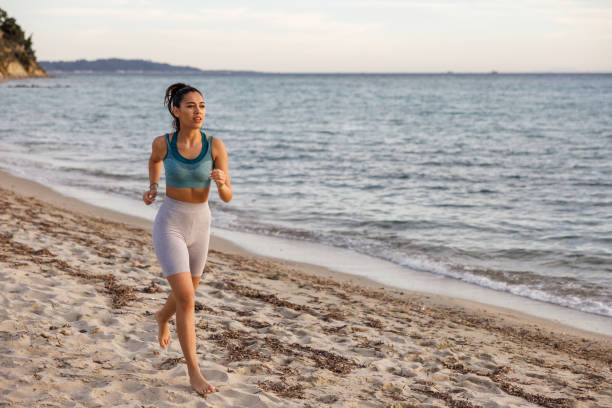 istock Young woman jogging on the beach 2154548207