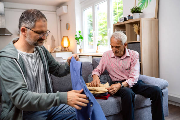istock Adult son folding clothes for his senior father 2154554998