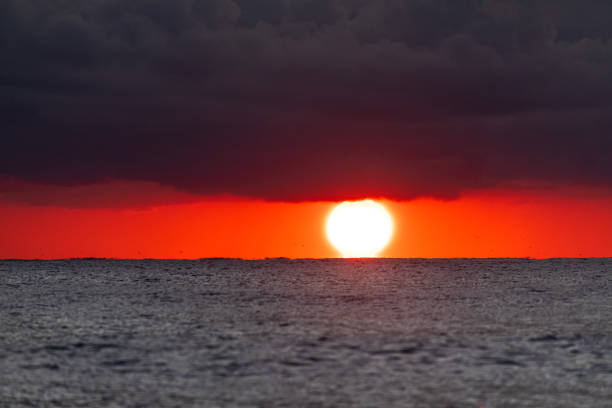 Orange sunrise with dramatic storm clouds over the ocean