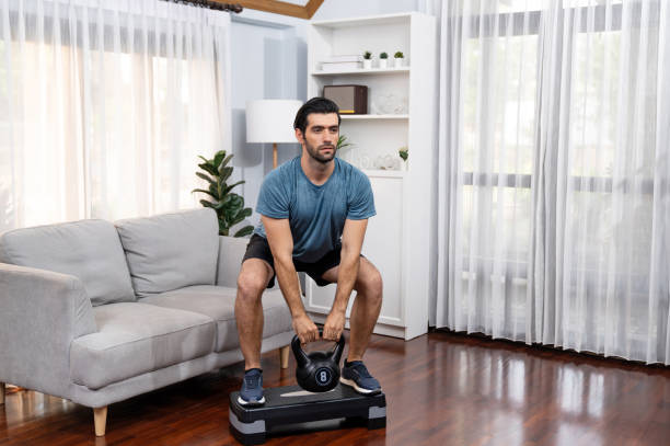 istock Athletic body and active sporty man lifting kettlebell at gaiety home exercise. 2154558430