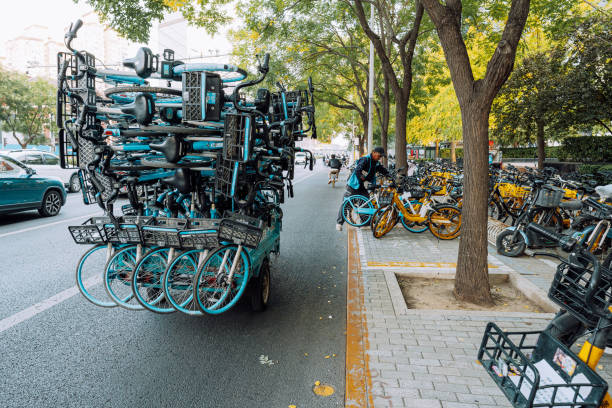 A worker organizes shared bicycles in Beijing, China on October 10th, 2023. The image shows an efficient bike-sharing service in a urban setting.