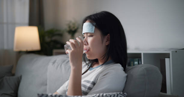 istock Sick young woman drinking water on the sofa at home. 2154560974