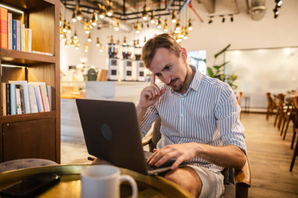 istock Young man working on his laptop while sitting in a cafe 2154568320