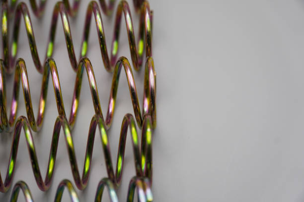 steel compression coil springs with varied surface finish isolated on grey background. Springy metallic machine parts. Set of different flexible elastic shock absorbers with spiral wire winding.