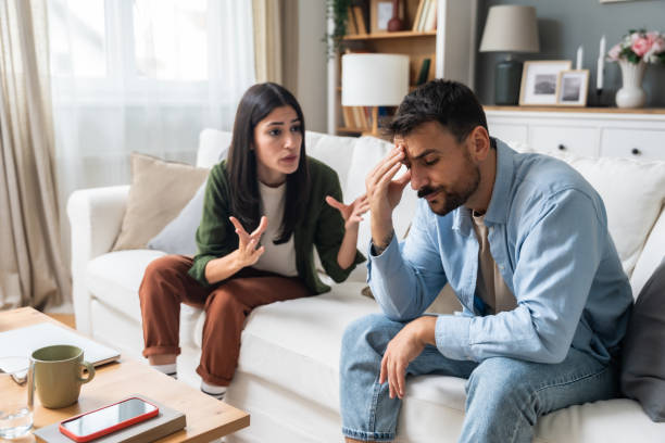 istock Communication problems, relationship difficulties. Young couple man and woman sitting on sofa at home, argue and misunderstanding. Two angry and sad people having issue with ego and guilt. 2154572429
