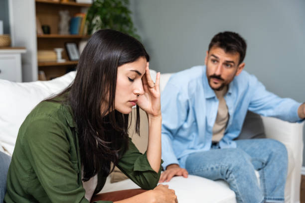 istock Communication problems, relationship difficulties. Young couple man and woman sitting on sofa at home, argue and misunderstanding. Two angry and sad people having issue with ego and guilt. 2154572433