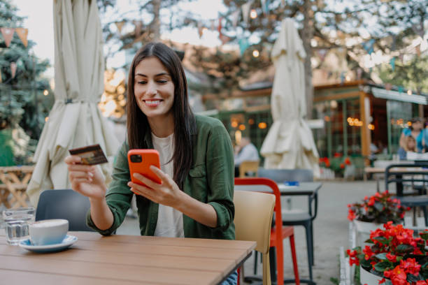 istock Woman holding card and smartphone at cafe 2154575656