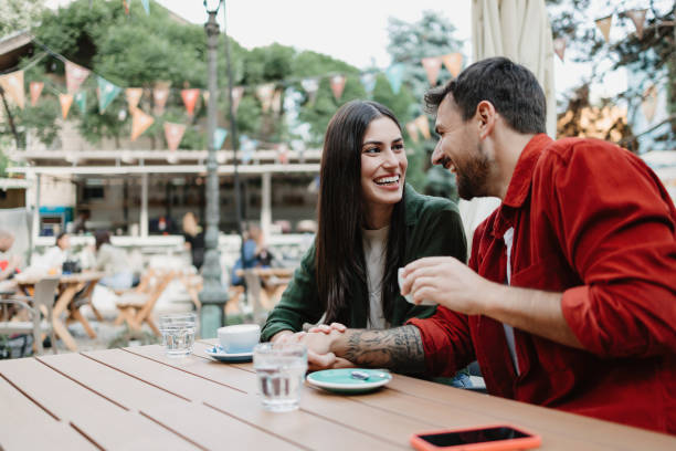 istock Couple laughing and holding hands at cafe 2154576348