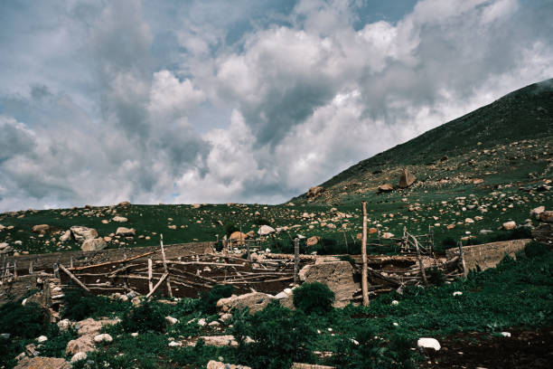 Scenic mountain valley features aged wooden fence and cattle stable