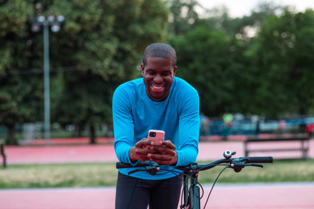 istock Smiling man with bicycle using smart phone in park 2154587860