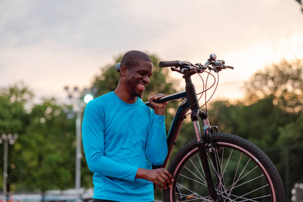 istock Smiling man holding a bicycle in the park at sunset 2154587866