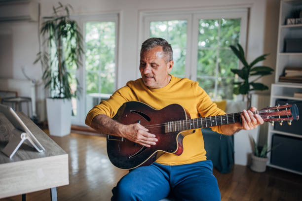 istock Senior man playing guitar at home 2154588077