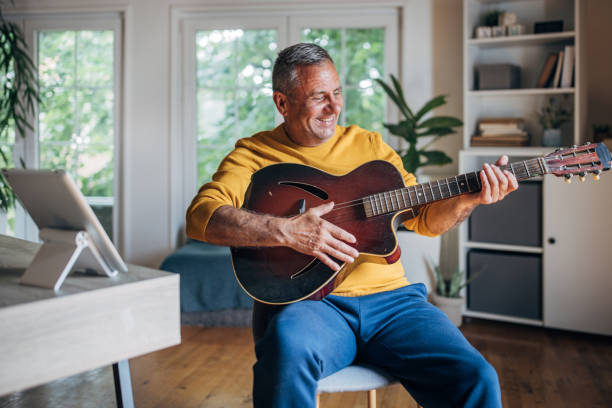istock Joyful senior man playing guitar at home 2154588106