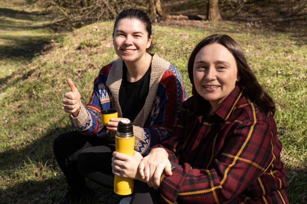 istock two young women on a picnic, sitting with a yellow thermos 2154589263