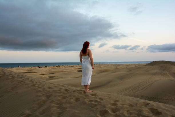 istock Young woman stands with her back in the sand dunes 2154589720