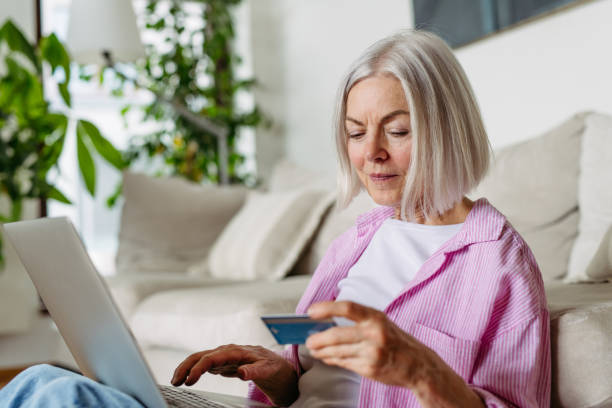 istock Mature woman paying with debit, credit card online, using internet banking and payment gateway. Shopping online, risk of frauds and hoax. 2154589749