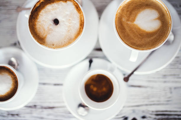 Cups with hot espresso, cappuccino and latte on table.