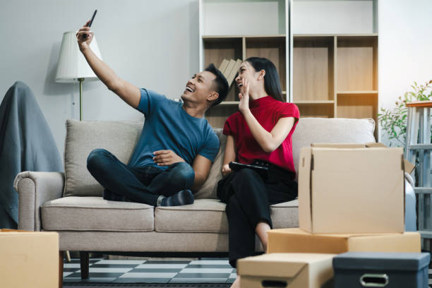 istock Young couple relaxing sitting on the sofa using the computer laptop around cardboard boxes, very happy moving to a new house. 2154603174