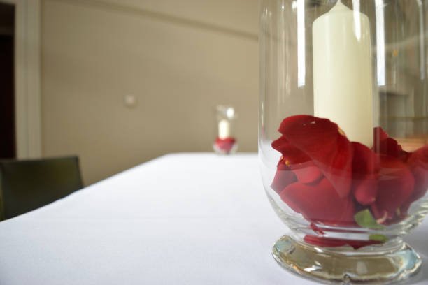 istock White candle with red rose petals in glass vase 2154607294
