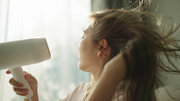 istock Young woman blow drying hair. 2154608672
