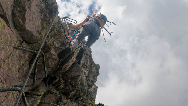 istock Young woman climbs cliff on via ferrata 2154614904