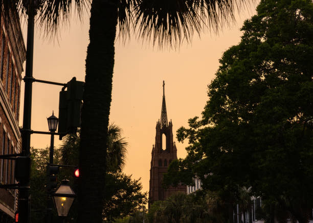 A beautiful golden hour silhouette scene before sunset of Charleston with the tall steeple of Cathedral of Saint John the Baptist in the center.  HDR encoded.