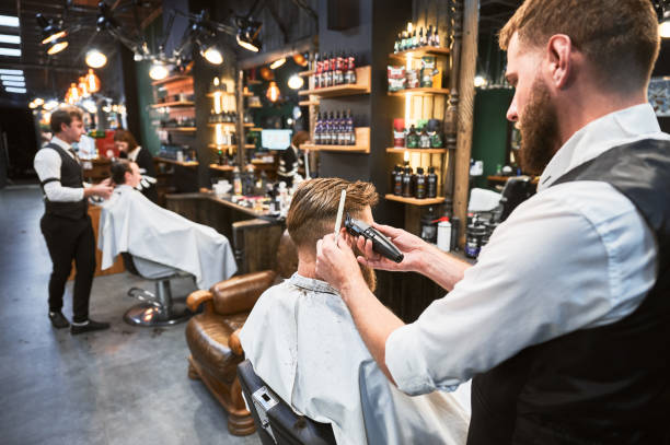 istock Professional barber using comb and electric shaver to cut side hair. 2154621772