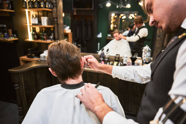 istock Close-up of experienced barber using comb and scissors to cut extra hair. 2154621789