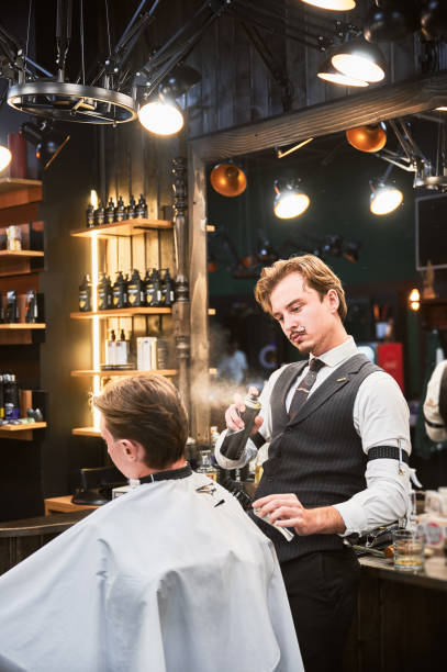 istock Professional barber using hairspray to finish hairstyle. 2154621797