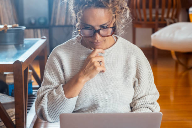 istock Vertical portrait of modern woman using computer at home thinking for solution or reading email. Modern people lifestyle and technology connection leisure indoor activity. Relaxation with laptop 2154623494