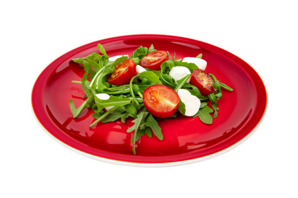 arugula with tomatoes and mozzarella on a red plate isolated on white