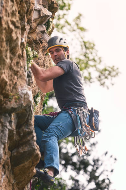 istock A man is climbing a rock face wearing a helmet. He is very focused on his task. 2154625485