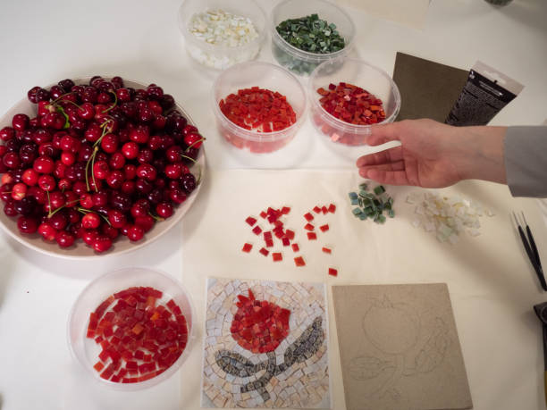 istock Crafting Mosaic: Man’s hand reaching for a plastic container with red mosaic. Vertical straight from above close up. 2154631474