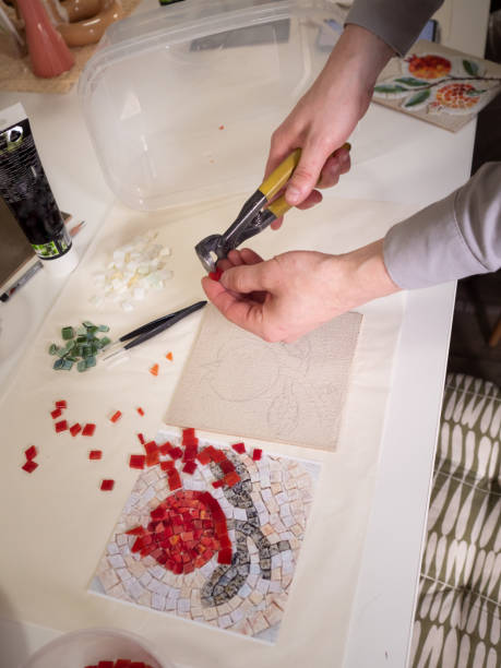 istock Crafting Mosaic: Man using pliers to shape a mosaic piece to the desired form. Vertical straight from above close up. 2154631476