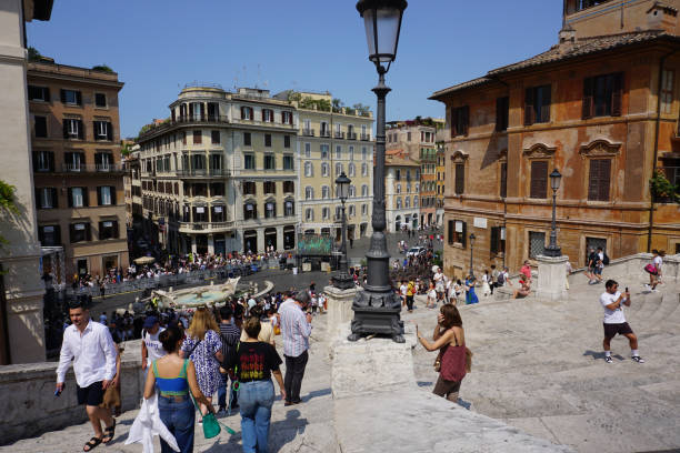 Rome, Italy - November 3, 2012: Trinita dei Monti Church and Spanish Steps in Rome, crowded with tourists. A family of tourists sitting on the steps during a visit in Rome, Italy