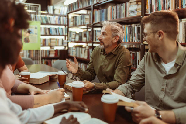 istock Male Professor Talking With His Students at Library 2154637606