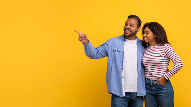 istock Man and Woman Pointing at Something on Yellow Background 2154637916