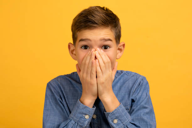 istock Teenage boy with shocked expression covering his mouth with both hands 2154643335