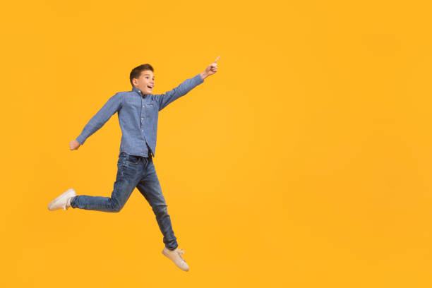 istock Look At This. Teen boy pointing aside while jumping up in air 2154643346