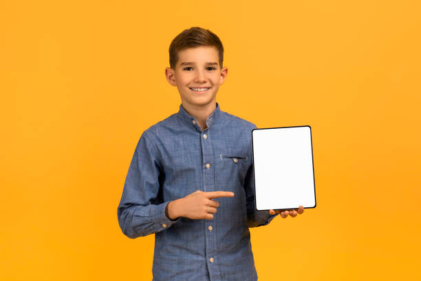 istock Smiling teen boy pointing at tablet with blank white screen 2154643394