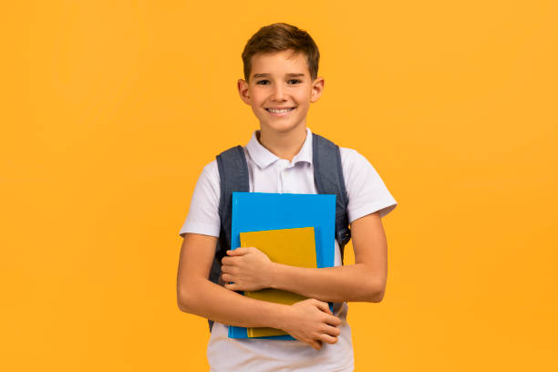 istock Smiling teen schoolboy with backpack holding textbooks and smiling at camera 2154643401