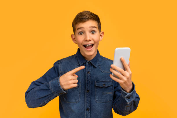 istock Happy teen boy pointing at smartphone with excited expression 2154643480