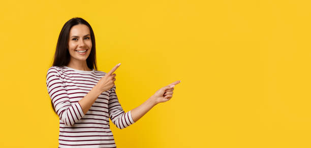 istock Excited Young Woman Pointing Aside At Copy Space On Yellow Background 2154643845